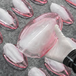 Seraphina Rose Glass Petal Chandelier | Glass, Metal | A gloved hand carefully holding up a single molded translucent pink glass petal component to demonstrate its textured surface and size | Detail shot | Severn Lighting