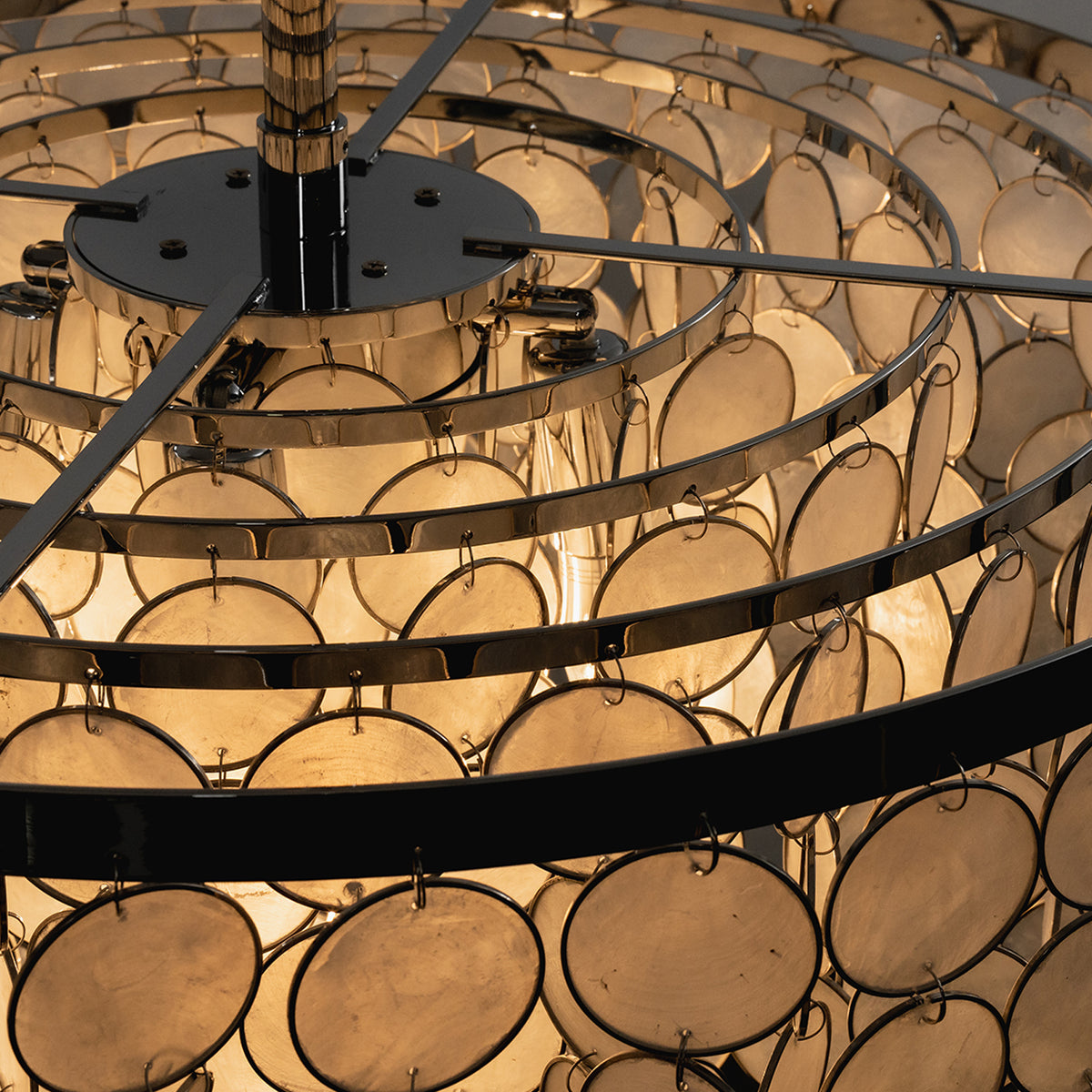 Sirena Capiz Disc Tiered Ceiling Light | Shell, Metal | Close-up top view showing the concentric black metal ring framework and ring links holding the shell discs | Detail shot | Samu Lamp