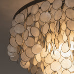 Sirena Capiz Disc Tiered Ceiling Light | Shell, Metal | Close-up side profile of the overlapping shimmering shell discs illuminated to reveal natural patterns | Detail shot | Samu Lamp