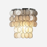 Sirena Capiz Tiered Wall Sconce | Capiz Shell, Metal | Half-drum tiered wall sconce featuring cascading translucent capiz shell discs and a polished chrome frame | Isolated lit product shot on white background | Samu Lamp