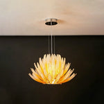 Solaris Agave Glass Starburst Chandelier | Amber Textured Glass | Minimalist frontal view of the glowing amber agave fixture on a solid dark charcoal wall | Severn Lighting