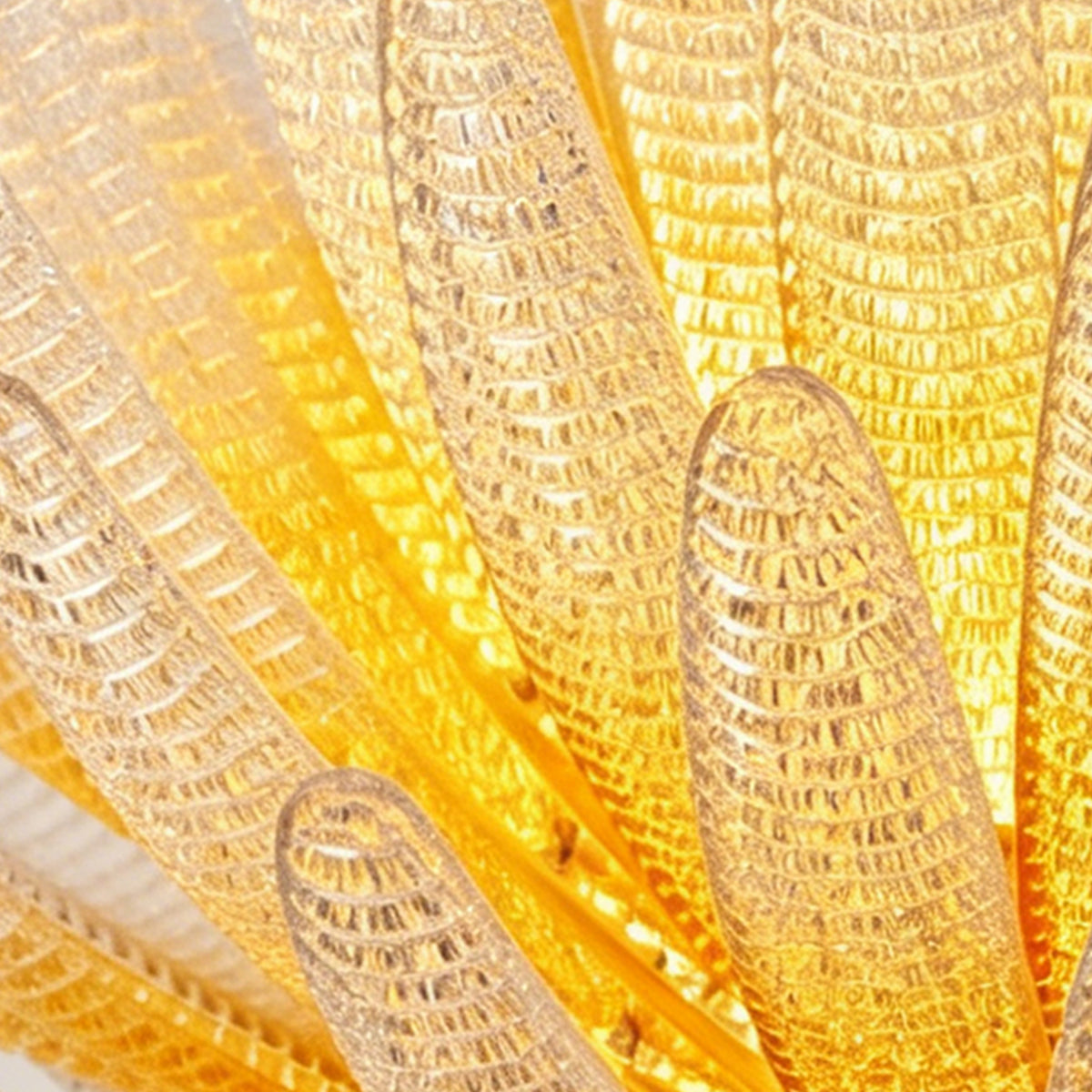 Solaris Agave Glass Starburst Chandelier | Amber Textured Glass | Macro shot focusing on the bubbly textured details of the illuminated golden glass leaves | Severn Lighting