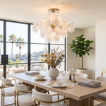 Solene Clustered Glass Disc Ceiling Light | Clear and Frosted Glass Discs | Hanging above a modern wooden dining table in a room with a palm tree window view | Severn Lighting