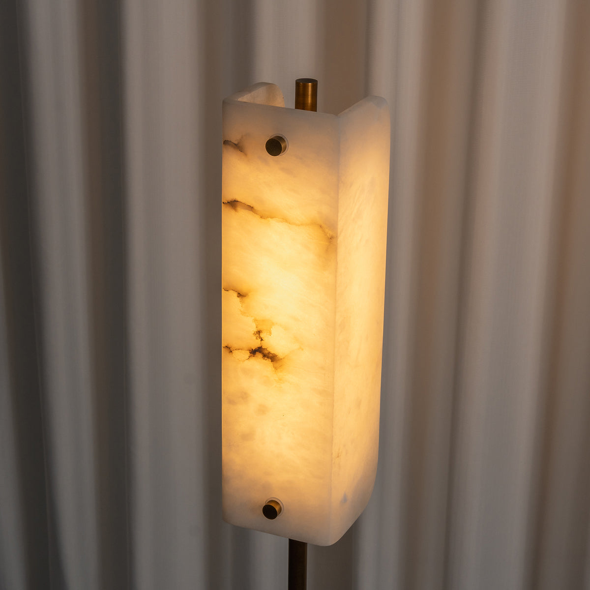Stellan Alabaster Column Floor Lamp | Natural Alabaster, Brass and Black Metal | Medium shot highlighting the warm glowing alabaster column | Severn Lighting
