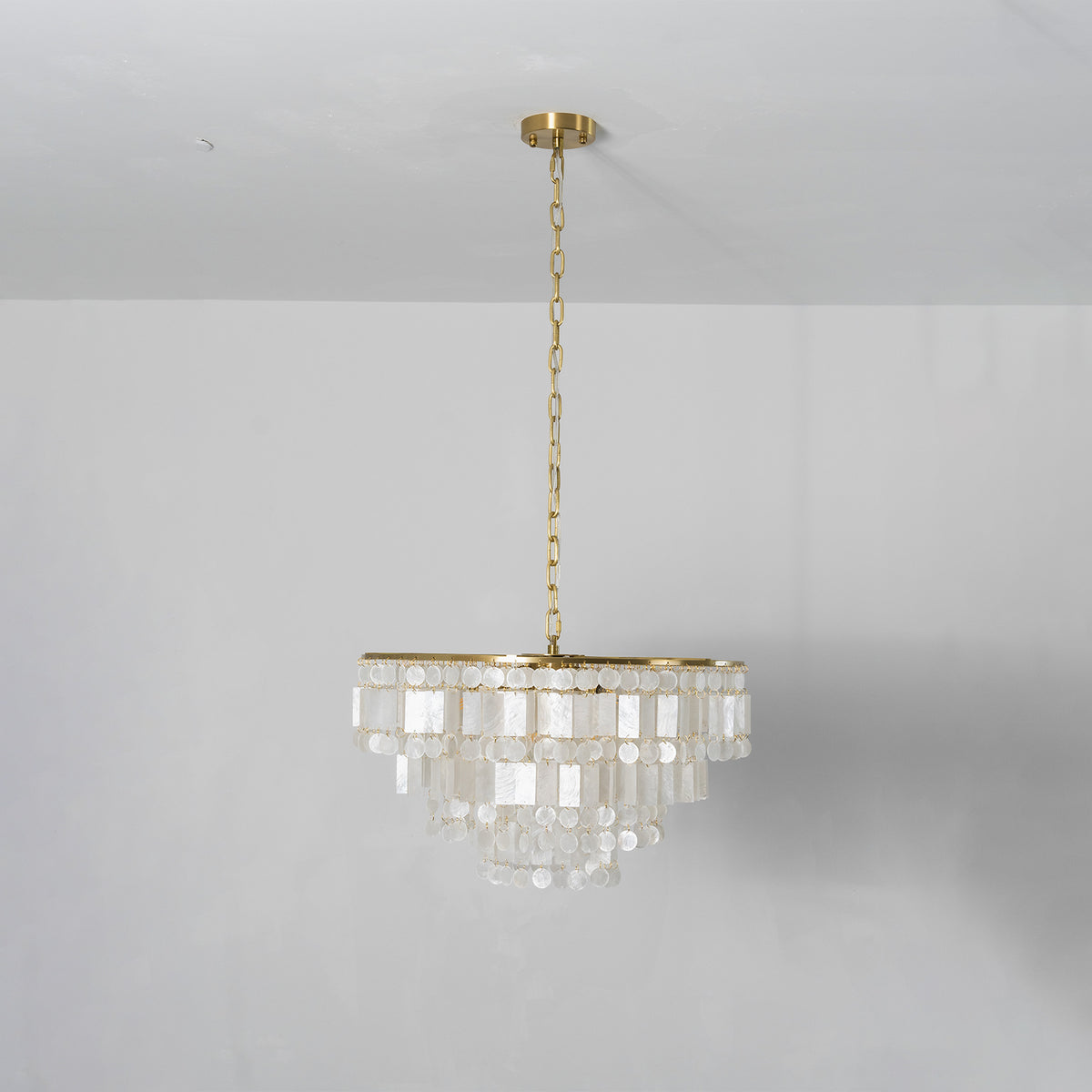 Thalassa Tiered Capiz Shell Chandelier | Capiz Shell, Metal | Front centered studio shot of the unlit white capiz shell chandelier variant suspended against a clean off-white wall | Severn Lighting