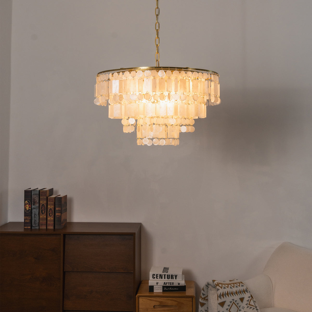 Thalassa Tiered Capiz Shell Chandelier | Capiz Shell, Metal | Staged against a plain textured wall over a dark wooden console cabinet, casting soft warm light in an elegant setting | Severn Lighting