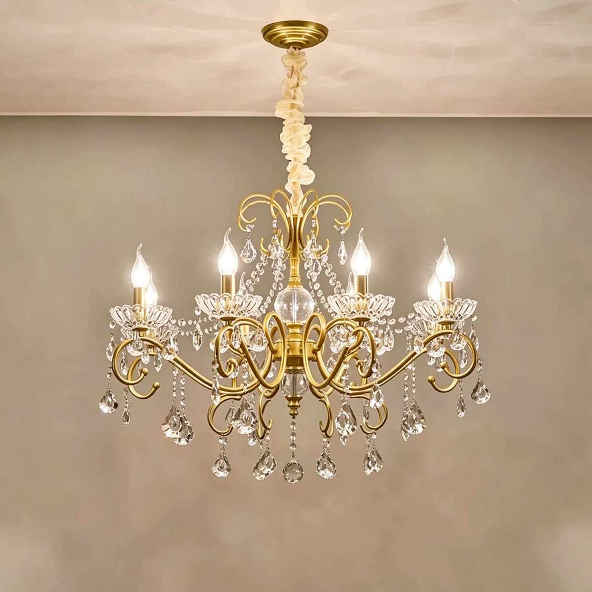 Torvald Scrolled Crystal Brass Chandelier | Cut Crystal and Brass | Medium size variant illuminated full view displayed against a neutral wall | Severn Lighting