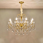 Torvald Scrolled Crystal Brass Chandelier | Cut Crystal and Brass | Medium size variant illuminated full view displayed against a neutral wall | Severn Lighting