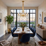 Torvald Scrolled Crystal Brass Chandelier | Cut Crystal and Brass | Hanging in a luxury dining room with blue velvet chairs and large windows | Severn Lighting