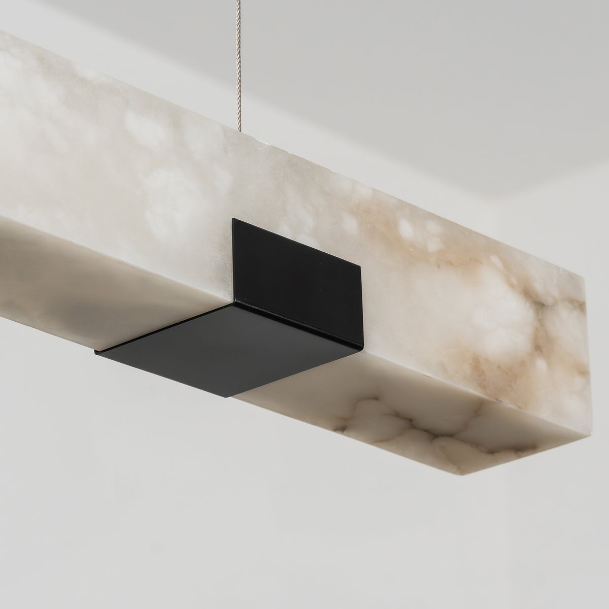 Vale Alabaster Linear Glow Pendant Lighting | Natural Alabaster and Black Metal | Detailed close-up view highlighting the rectangular stone end and black mounting bracket | Severn Lighting