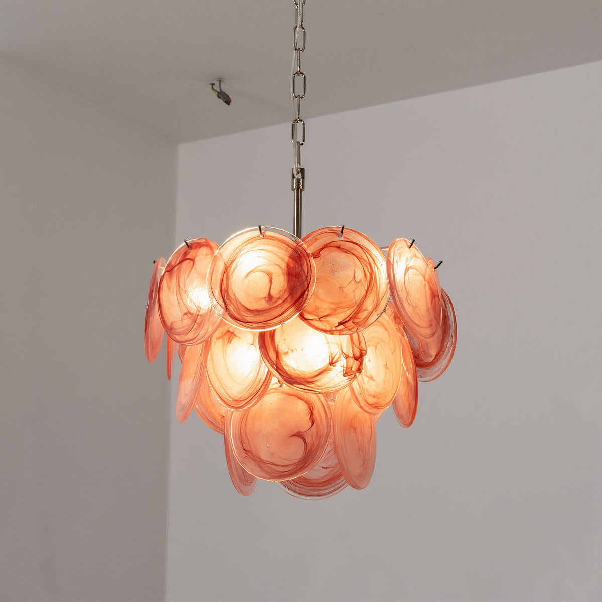 Vaucelle Swirled Glass Disc Tiered Chandelier | Swirled Glass and Brass | Full product shot of pink swirled glass disc variant illuminated | Severn Lighting