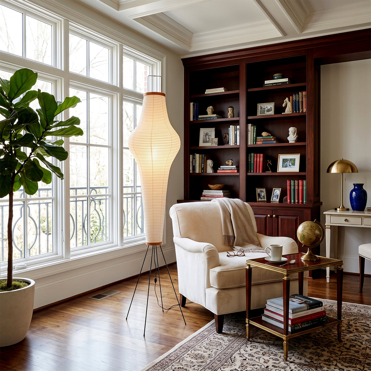Verena Ribbed Paper Column Floor Lamp | Ribbed Paper and Metal Tripod Legs | Standing in a sophisticated home library study room near dark wood bookshelves and an armchair | Severn Lighting