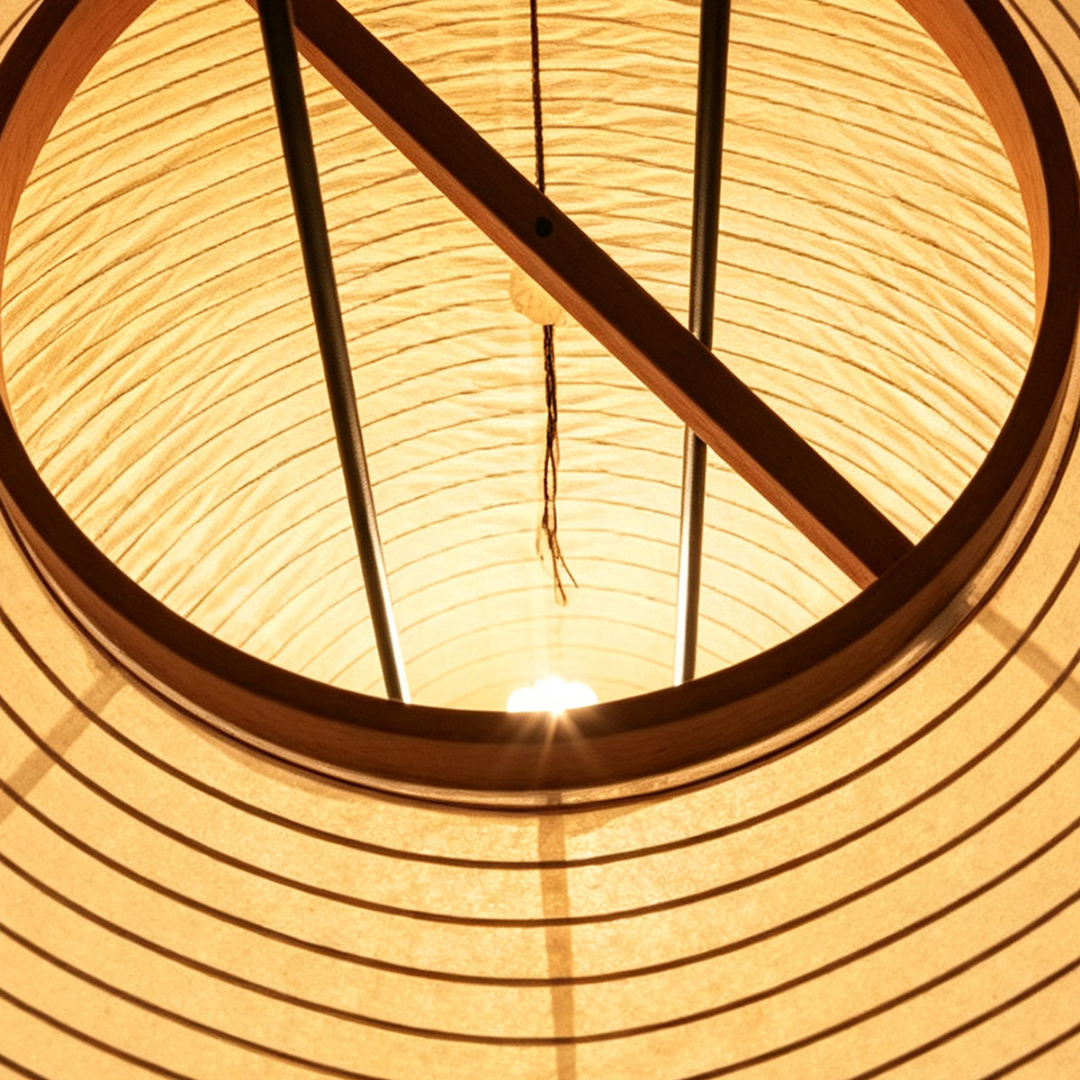 Verena Ribbed Paper Column Floor Lamp | Ribbed Paper and Metal Tripod Legs | Looking inside the lit paper shade showing the internal geometric wood bracing and wiring structure | Severn Lighting