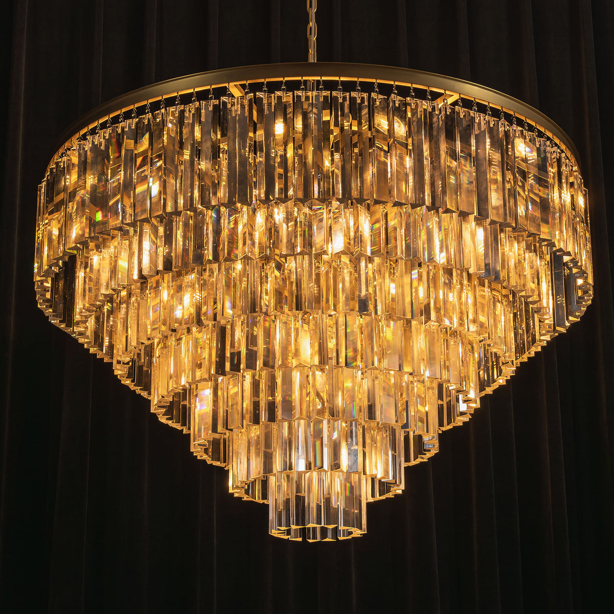 Verity Fringed Glass Tier Chandelier | Fringed Glass and Brass | Full view of the tiered chandelier glowing against a dark background | Severn Lighting