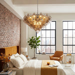 Vespera Tiered Smoked Glass Chandelier | Textured Smoked Glass | Casting a warm glow in a luxury loft bedroom featuring an exposed red brick wall | Severn Lighting