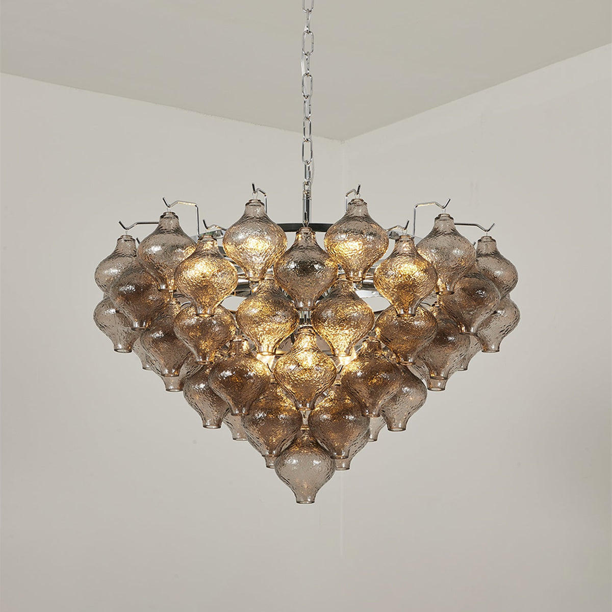 Vespera Tiered Smoked Glass Chandelier | Textured Smoked Glass | Full view of the fixture hanging from a plain ceiling fully lit with a warm golden ambiance | Severn Lighting