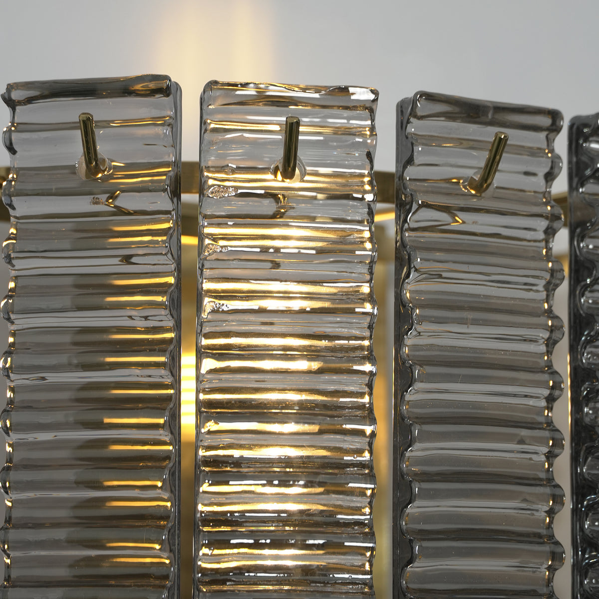 Vespera Tiered Smoky Glass Wall Lamp | Glass, Metal | Detailed close-up showing the golden brass central support structure behind the semi-translucent textured glass panels | Detail shot | Severn Lighting
