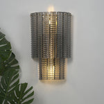 Vespera Tiered Smoky Glass Wall Lamp | Glass, Metal | Studio close-up of the fully illuminated tiered lamp casting a soft warm backlight halo against a neutral grey wall backdrop | Severn Lighting