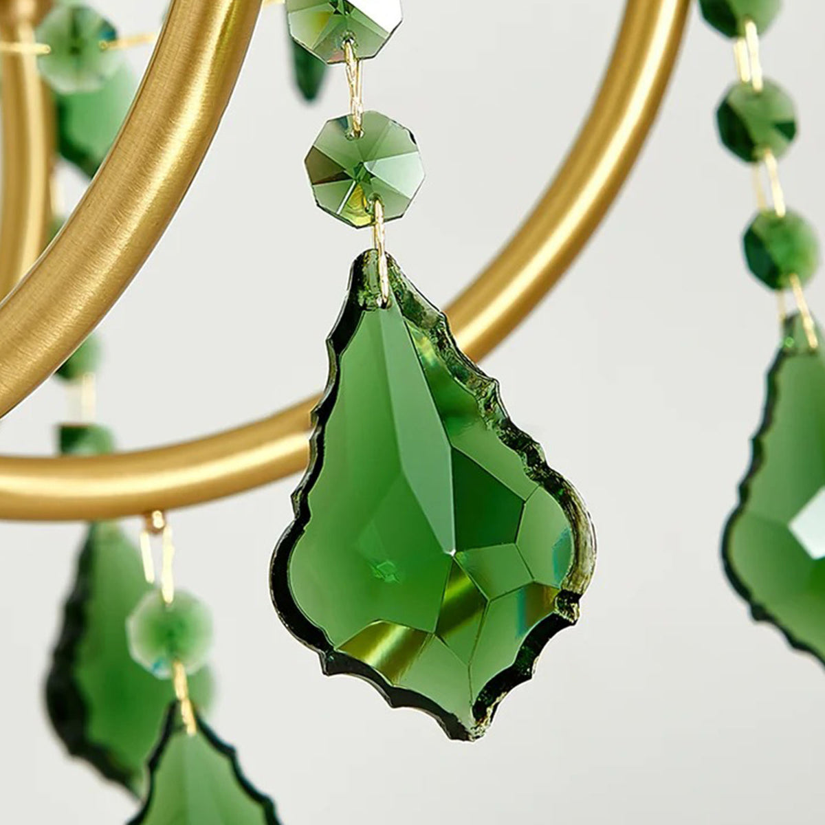 Vionne Green Crystal Drop Brass Chandelier | Green Crystal, Clear Glass and Brass | Macro close-up of a faceted emerald green crystal teardrop pendant | Severn Lighting