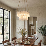 Vivienne Tiered Alabaster Chandelier | Alabaster, Brass | Hanging elegantly as a cozy dining centerpiece over a rustic wooden table with matching chairs in a bright stone-walled room | Severn Lighting