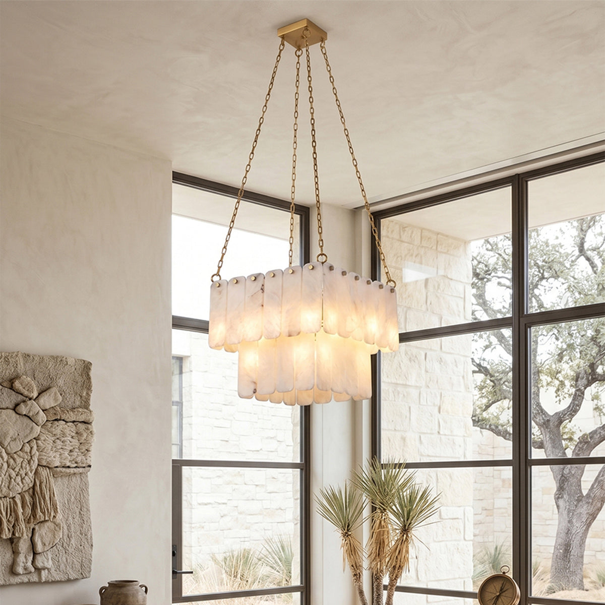 Vivienne Tiered Alabaster Chandelier | Alabaster, Brass | Studio styled view of the illuminated tiered stone chandelier hanging near a large grid glass window looking out to trees | Severn Lighting