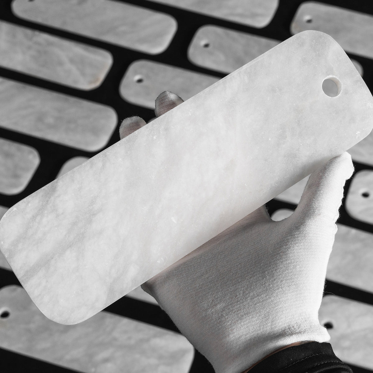 Vivienne Tiered Alabaster Chandelier | Alabaster, Brass | Detail shot showing a white-gloved hand holding an individual rectangular natural white alabaster stone tile slab | Detail shot | Severn Lighting